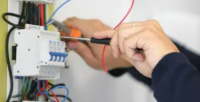 Electrician installing and adjusting circuit breakers in an electrical panel in Bakersfield, CA