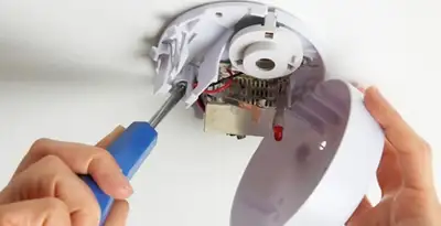 Certified technician wiring smoke detector during installation in Bakersfield, CA